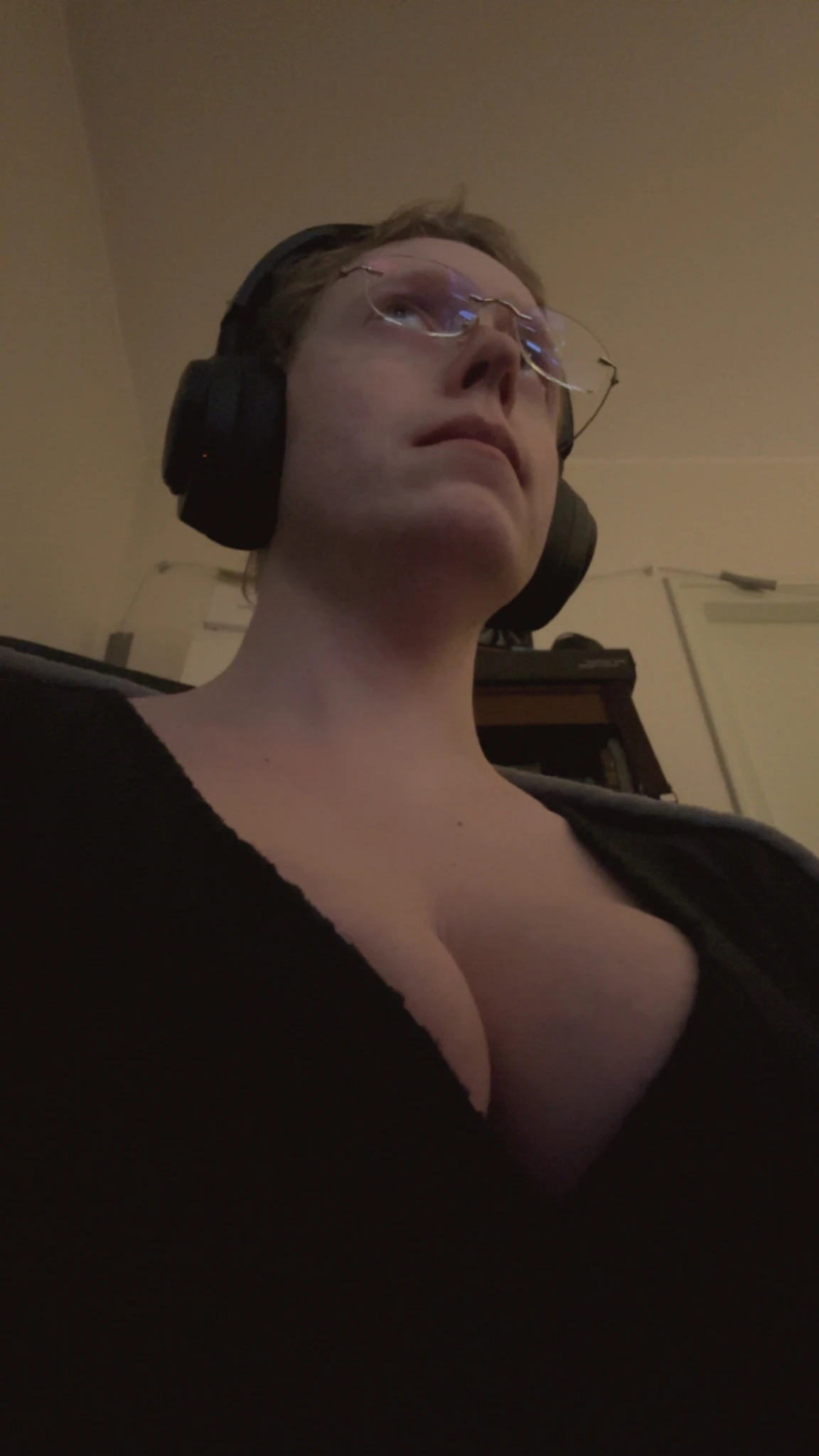 Low point of view of Siina, who is looking at her PC. She is wearing a low-cut dress and her cleavage is ample.